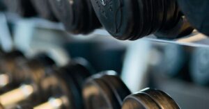 Home Close-up view of black dumbbells neatly arranged on a rack in a gym.